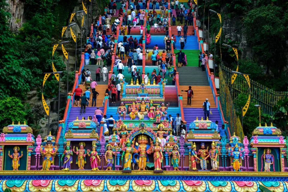 Climbers spread across the rainbow-painted 272 steps at Batu Caves, seen head-on from the base
