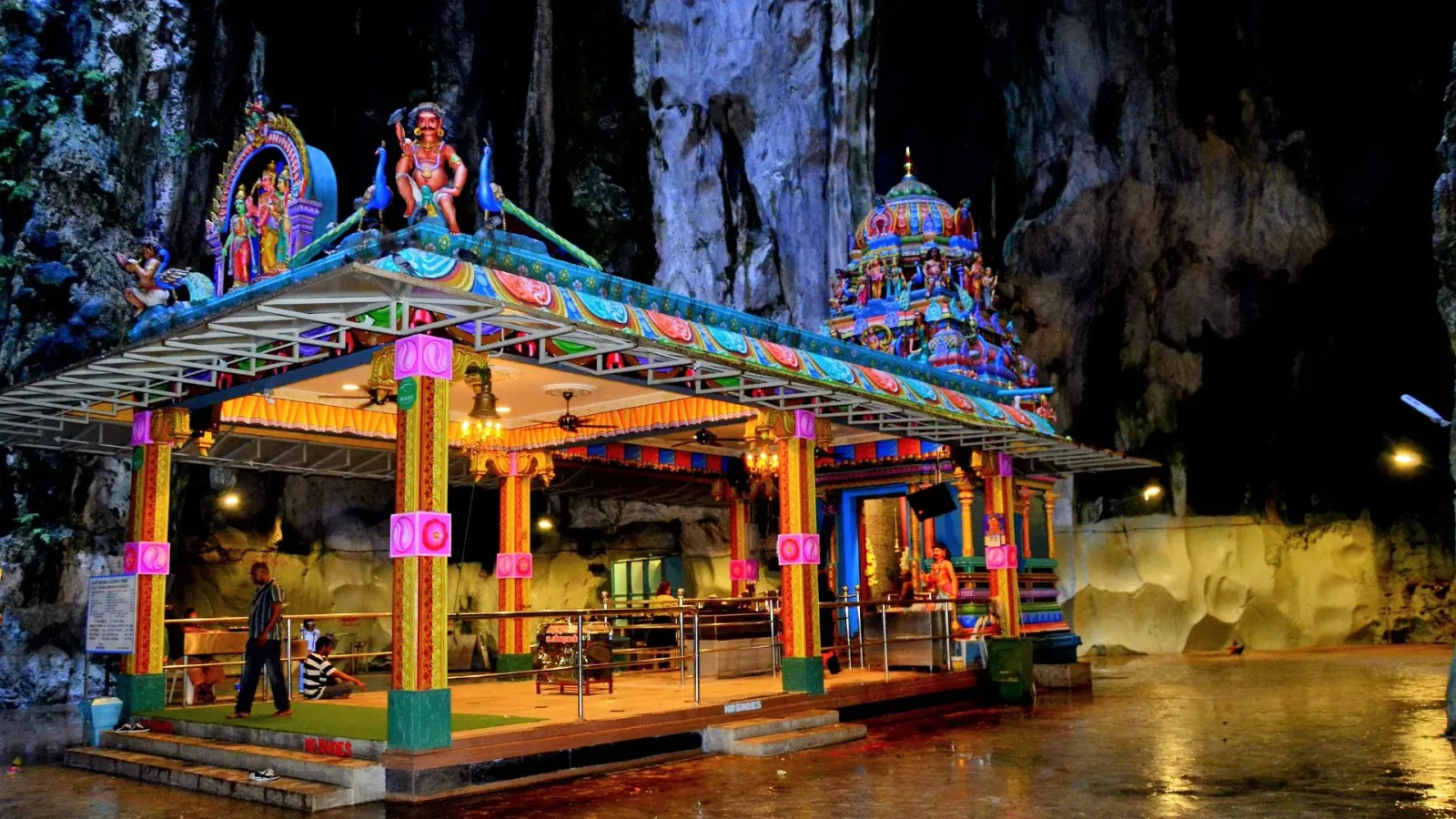 The painted shrine inside the Temple Cave at Batu Caves, with a priest at the sanctum