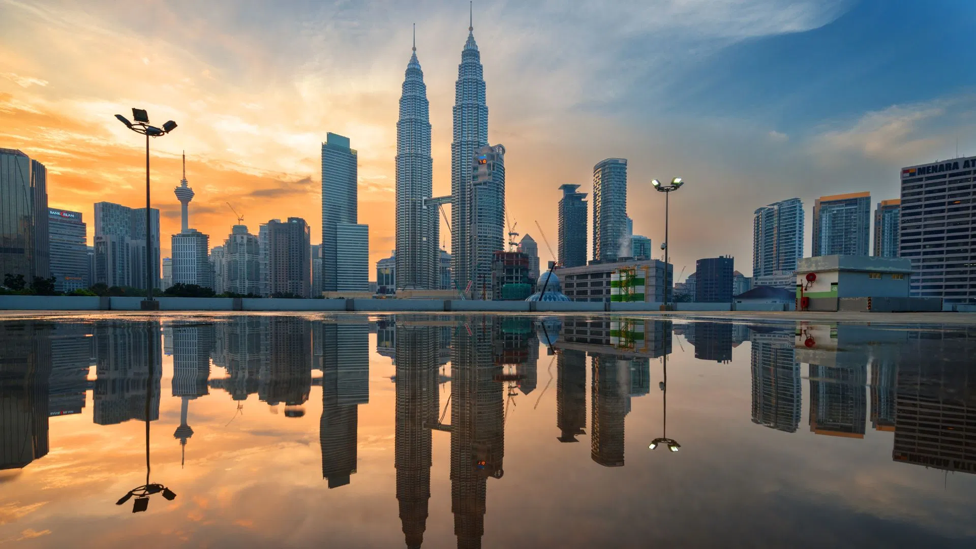 The Kuala Lumpur skyline reflected in still water at golden hour, the second half of a Batu Caves combo day